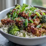 Steaming broccoli and simmering turkey in a sweet-spicy glaze creates a flavorful bowl topped with fresh green onions for a quick weeknight dinner.