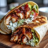 Creamy avocado and tangy mayo sauce peek from inside a golden, grilled Crispy Chicken Bacon Wrap.