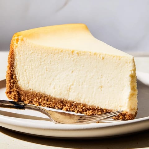 This rich New York Cheesecake features a dense, velvety texture and optional sour cream topping for a perfect dessert.