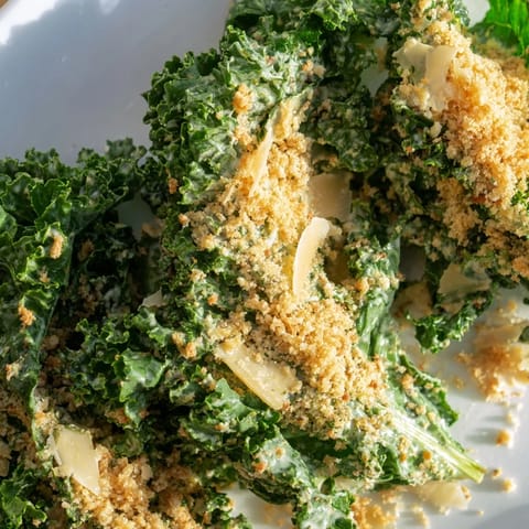 Garlic Parmesan Kale Salad tossed in a creamy dressing, topped with crunchy toasted breadcrumbs and shaved Parmesan.