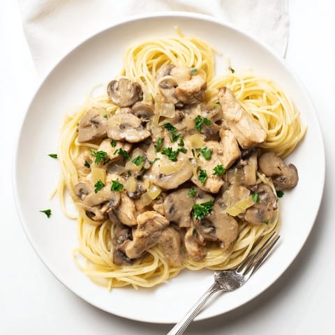 Creamy mushroom chicken spaghettini features tender chicken and al dente pasta coated in a velvety, light mushroom cream sauce, garnished with fresh parsley.