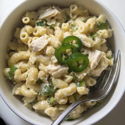 A close-up of Green Chili Chicken Mac shows melted cheese and tender chicken in a rich, Southwestern-style sauce.