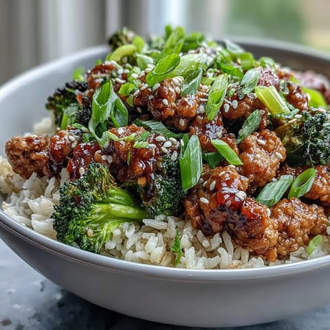 Steaming broccoli and simmering turkey in a sweet-spicy glaze creates a flavorful bowl topped with fresh green onions for a quick weeknight dinner.