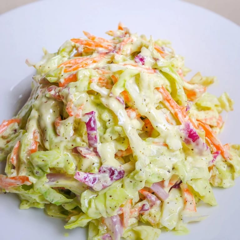 Classic American Coleslaw chilled and ready to serve, with tangy mayonnaise dressing and crunchy red onion slices on a plate.