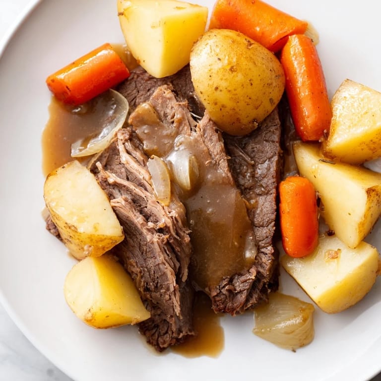 Fork-tender beef pot roast, golden vegetables, and a glossy brown gravy served for a hearty family dinner.  