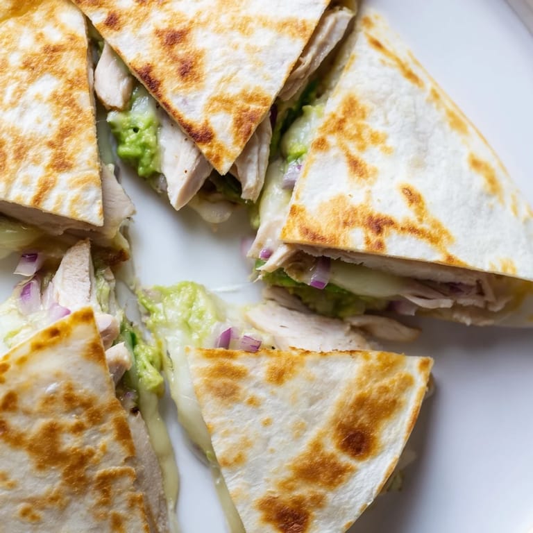 Perfectly golden-brown, the Chicken Avocado Quesadilla is served on a rustic wooden board with a lime wedge and fresh cilantro.